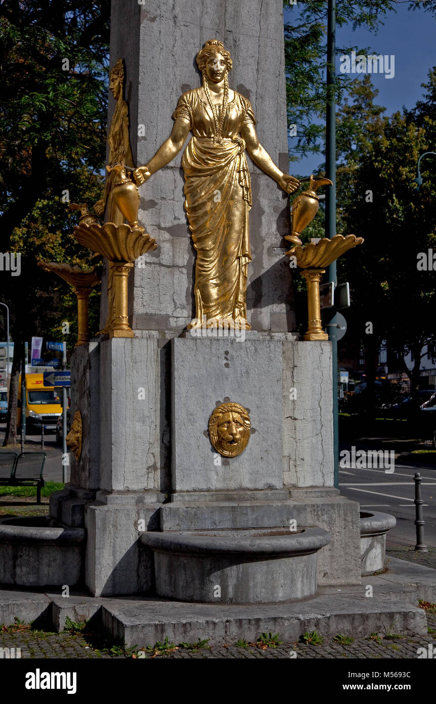 Aachen Trinkbrunnen HOTMANNSPIEF Errichtet 1825-30 Obelisco aus Blaustein mit vier gleichen vergoldeten gußeisernen weiblichen Halbrelieffiguren von Ad Foto de stock