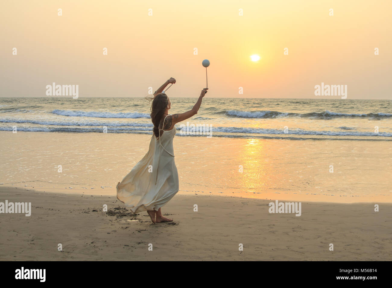 Mujer no identificada spinning poi en la playa. Foto de stock