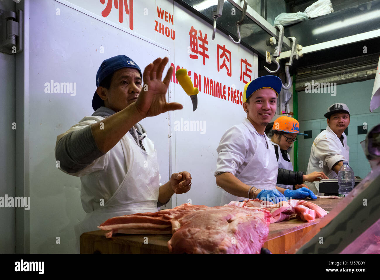 Roma, Italia: Algunos carniceros, la intención de cortar carne, jugar juegos de habilidad con el cuchillo en una carnicera China en el mercado de la plaza Vittorio Foto de stock