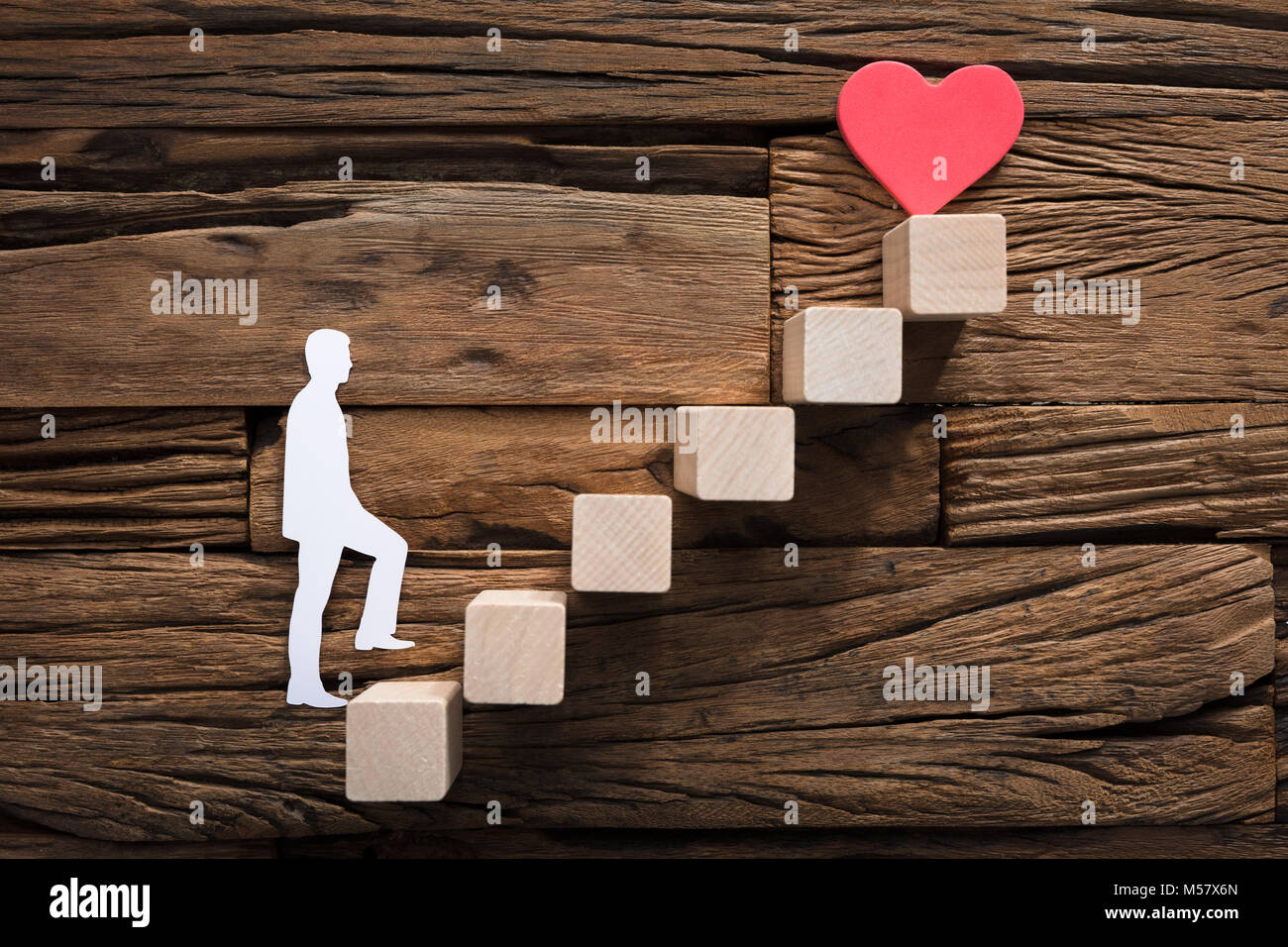 Primer plano de papel cortado hombre subía escaleras que conducen hacia el corazón y el amor Foto de stock