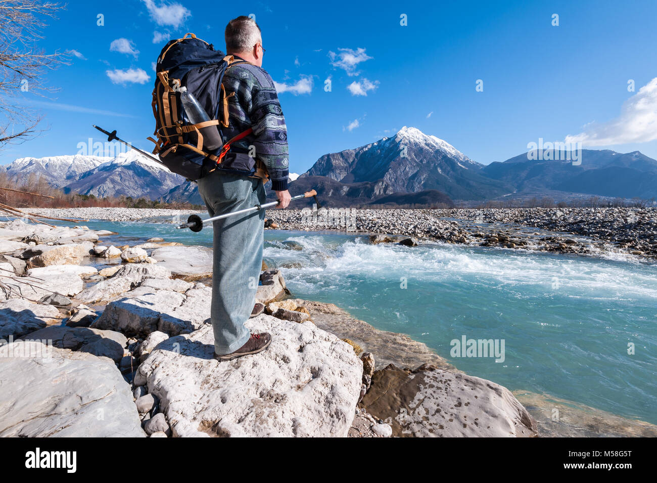 Excursionista de pie en la orilla del río, mirando el paisaje de las montañas. Alpes,Italia,Friuli. Foto de stock