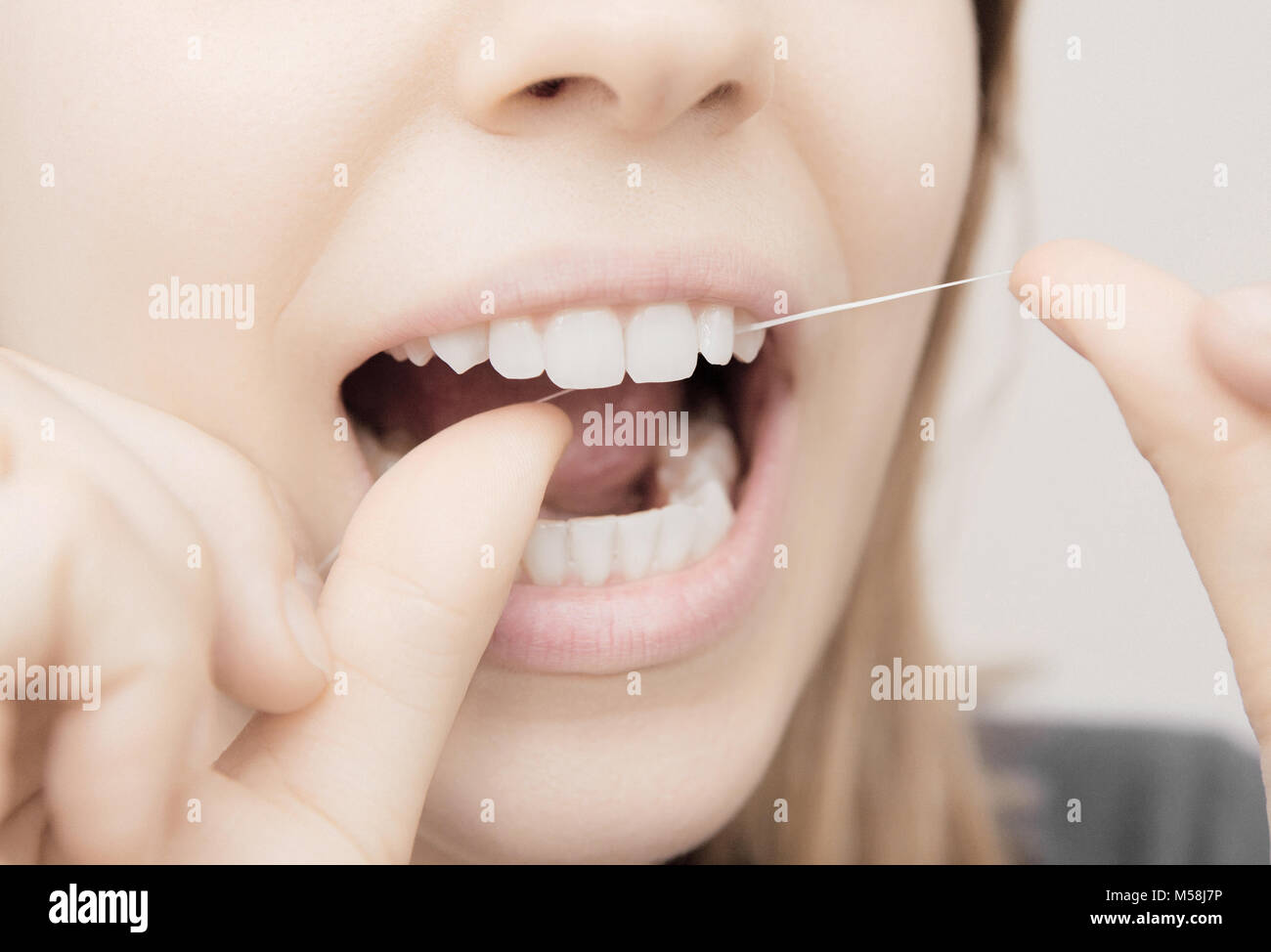 Mujer usa hilo dental en la boca, cuidado dental Foto de stock
