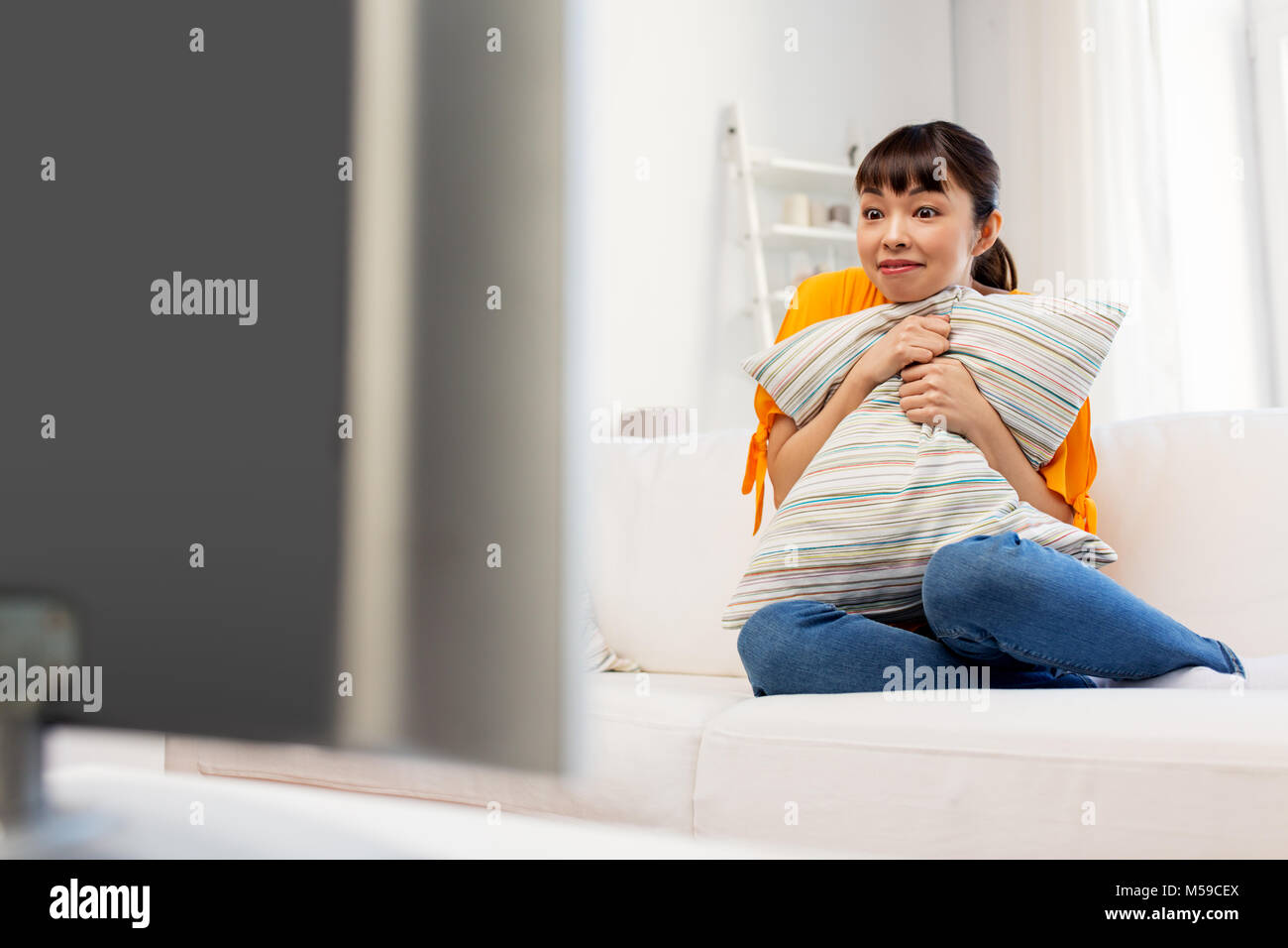 Aturdido mujer asiática con viendo la televisión en casa Foto de stock