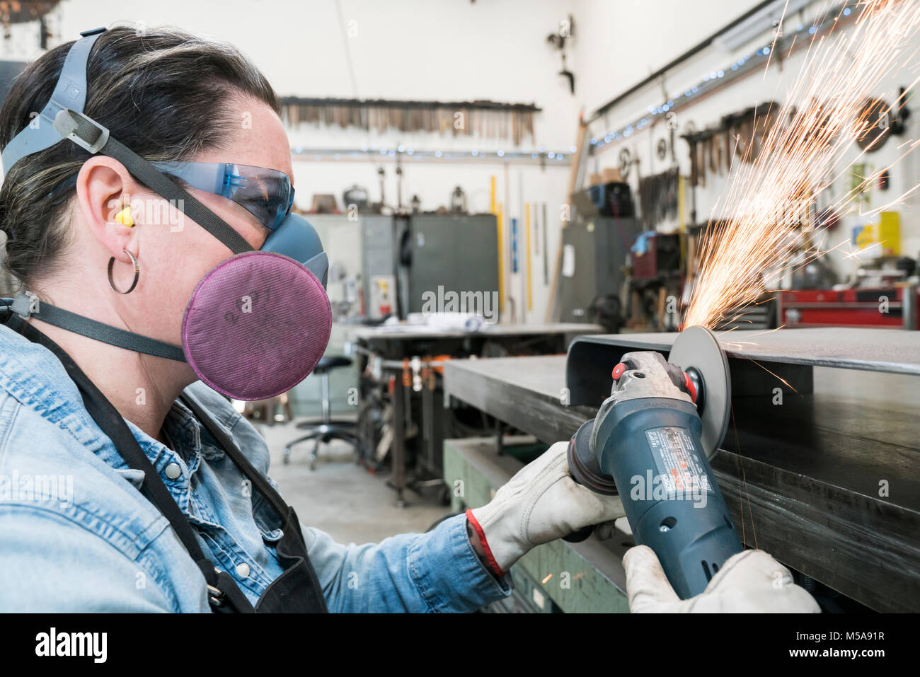 Mujer vistiendo gafas y máscara antipolvo de pie en taller metalúrgico,  utilizando power amoladora, chispas volando Fotografía de stock - Alamy