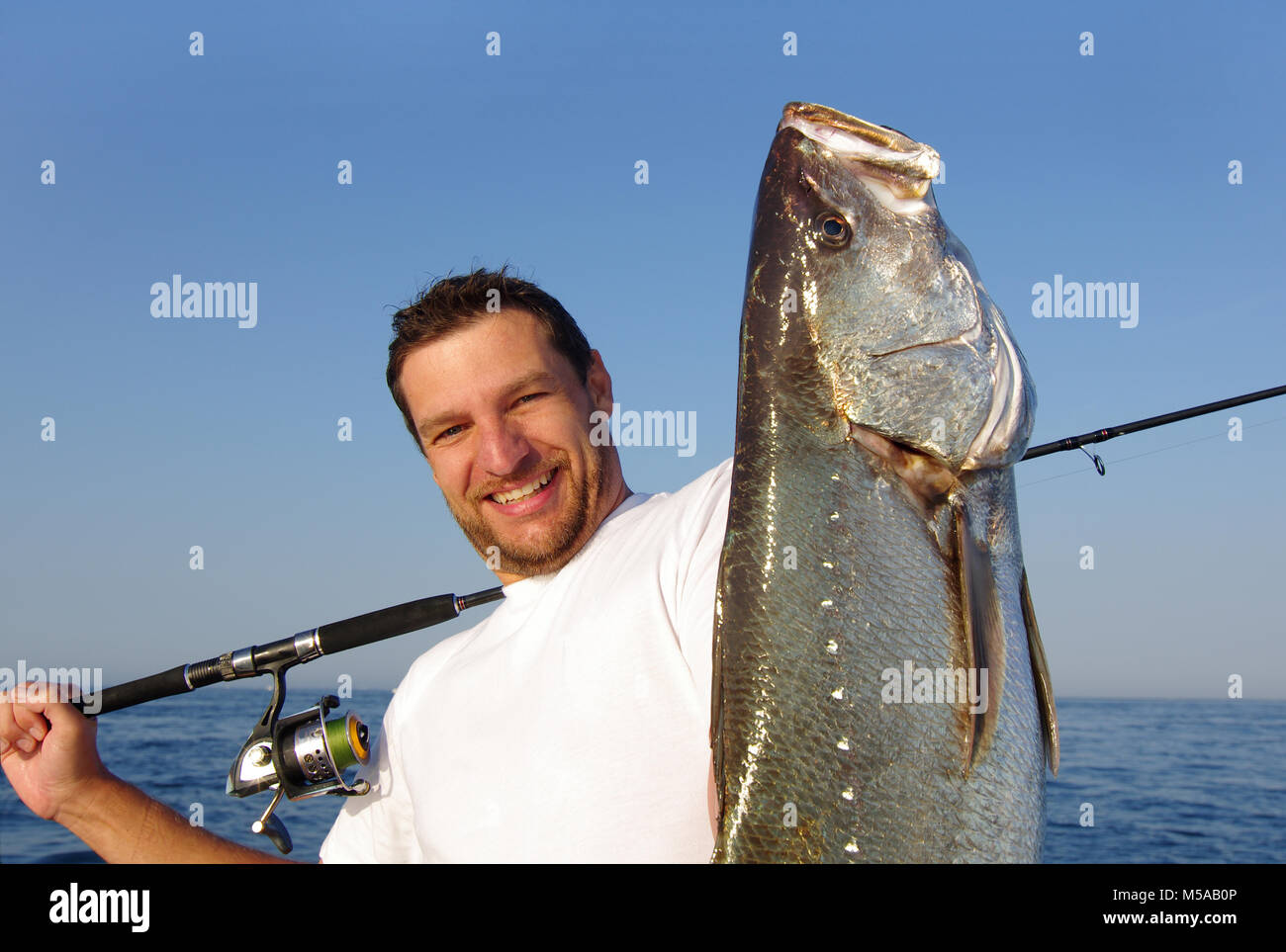 Feliz pescador sosteniendo un gran pez de agua salada Foto de stock