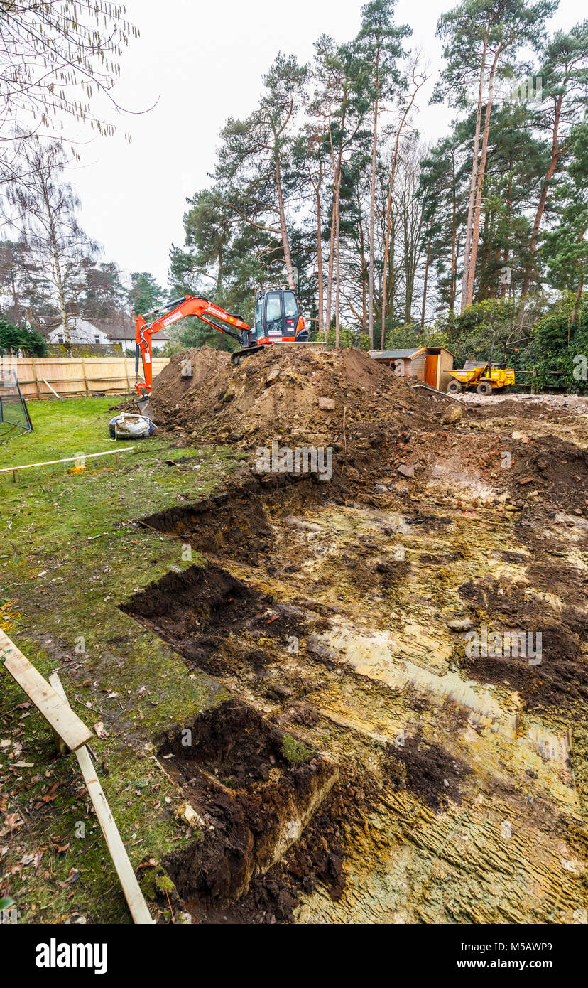 Gran naranja mecánica de maquinaria pesada excavadora aparcada en un montículo de tierra después excavando las excavaciones para los cimientos de un nuevo desarrollo residencial Foto de stock