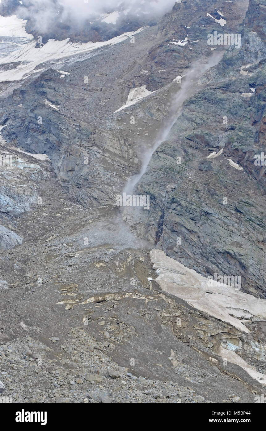 Un desprendimiento de rocas en las montañas causado por el derretimiento de los hielos. Caída de rocas provocando nubes de polvo aumentando a medida que caen y otras rocas de impacto, y se reúnen para fo Foto de stock