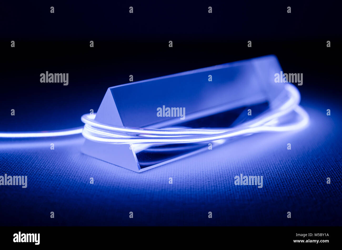 Un estudio bodegón fotografía de un prisma de vidrio triangular con iluminación de neón abstractos en violeta Foto de stock
