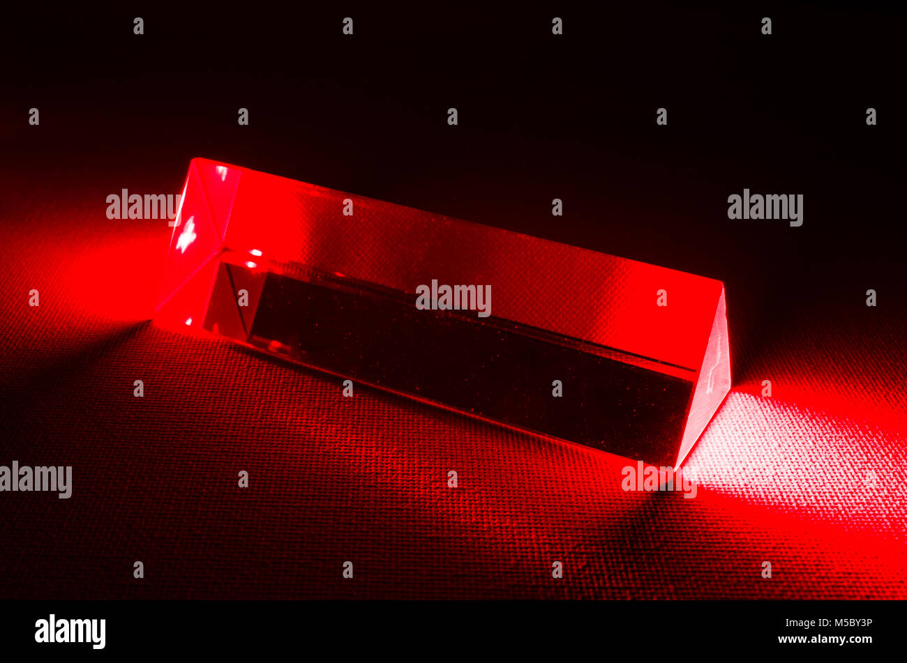 Un estudio bodegón fotografía de un prisma de vidrio triangular con luz roja del láser introduciendo el extremo del prisma Foto de stock