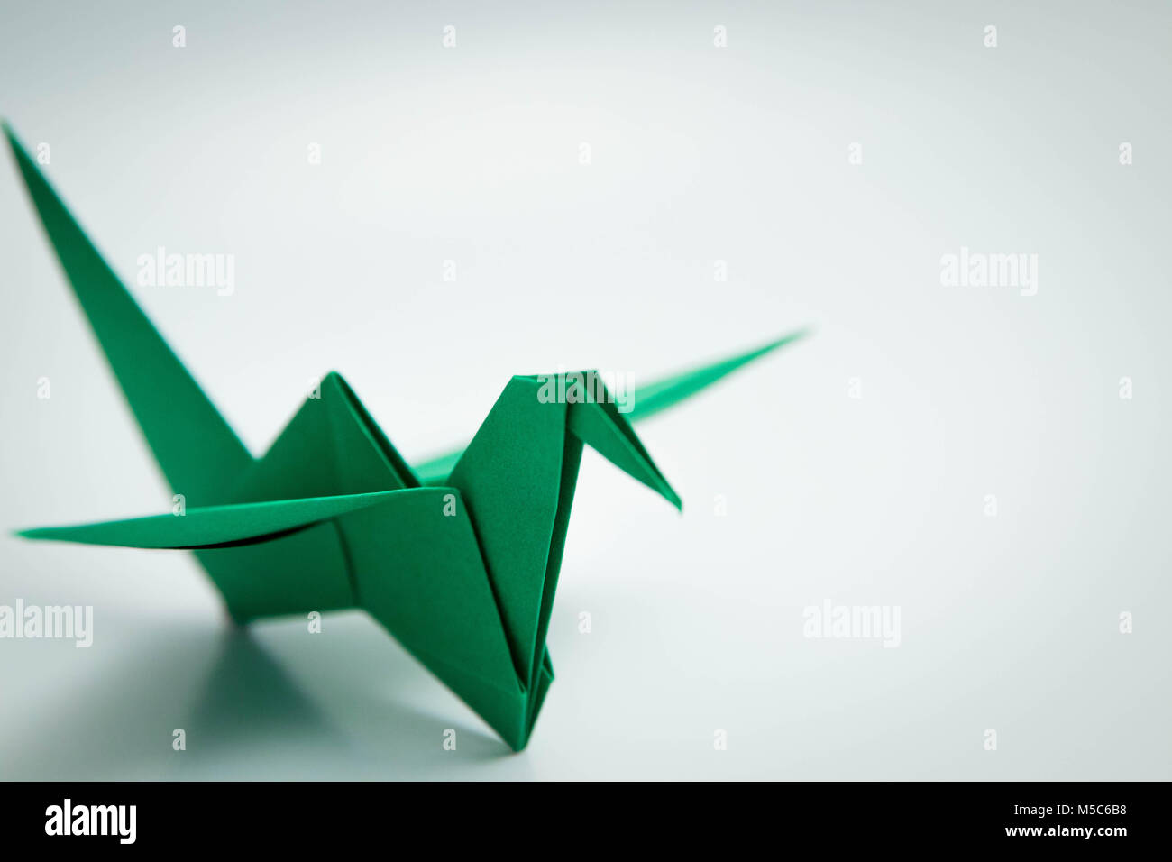 Pájaro verde simple origami aislado en blanco Foto de stock