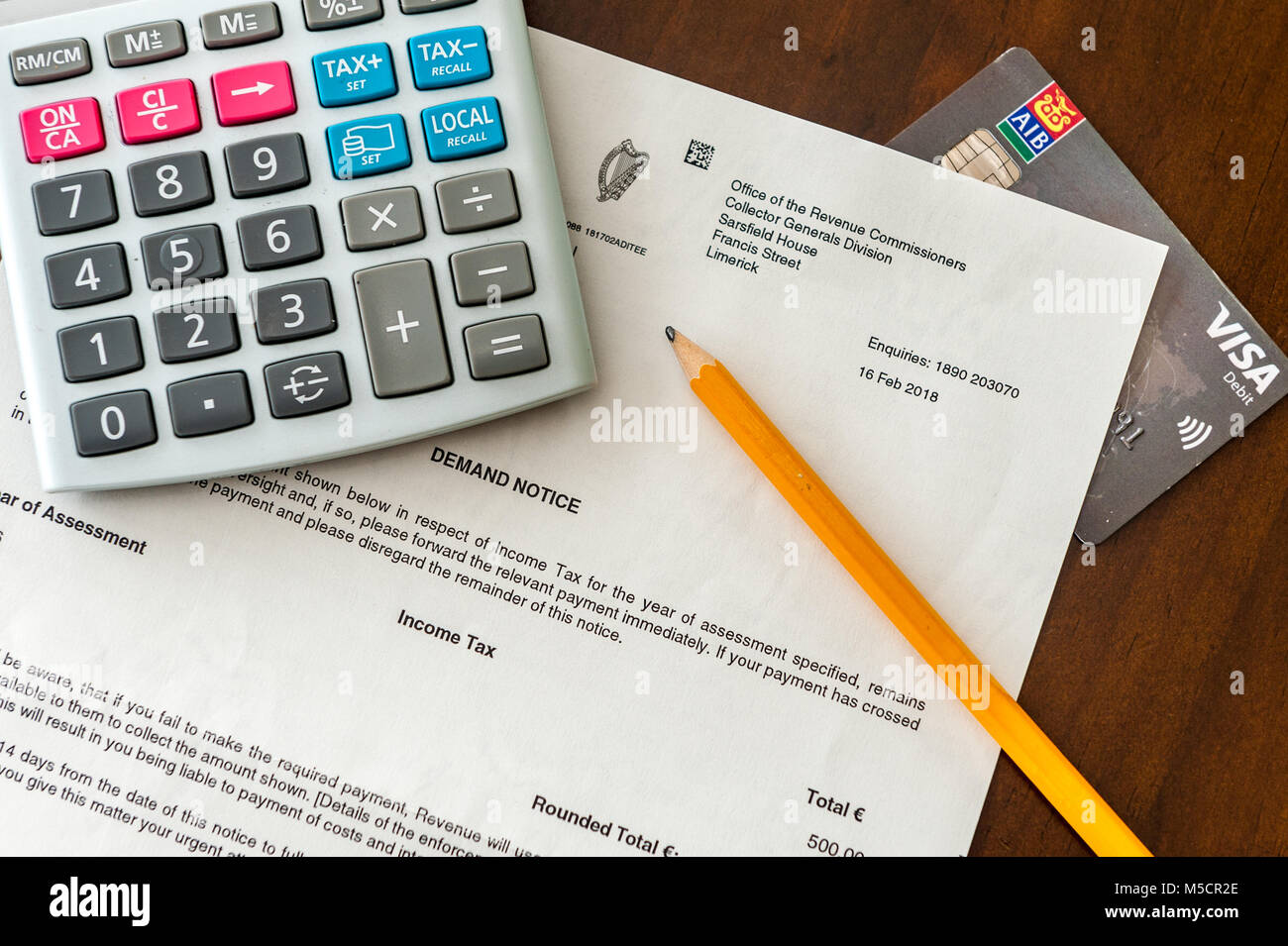 Carta de demanda de impuestos de €500 a partir de los ingresos irlandesa con una calculadora, lápiz y domiciliación bancaria/tarjeta visa. Foto de stock