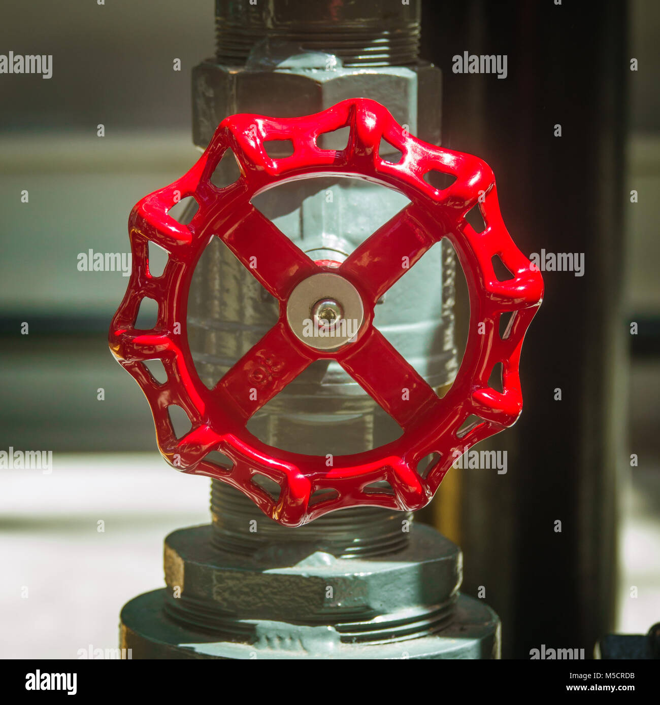 Rojo Válvula Industrial toca en un tubo metálico de una fábrica. Foto de stock