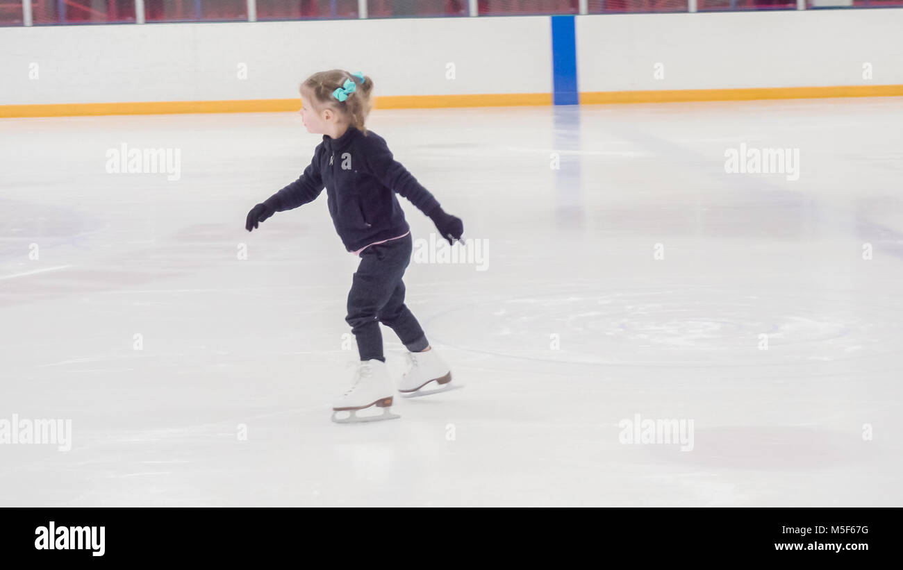Niña aprendiendo cómo indorr patinar en el hielo en la pista de patinaje sobre hielo. Foto de stock