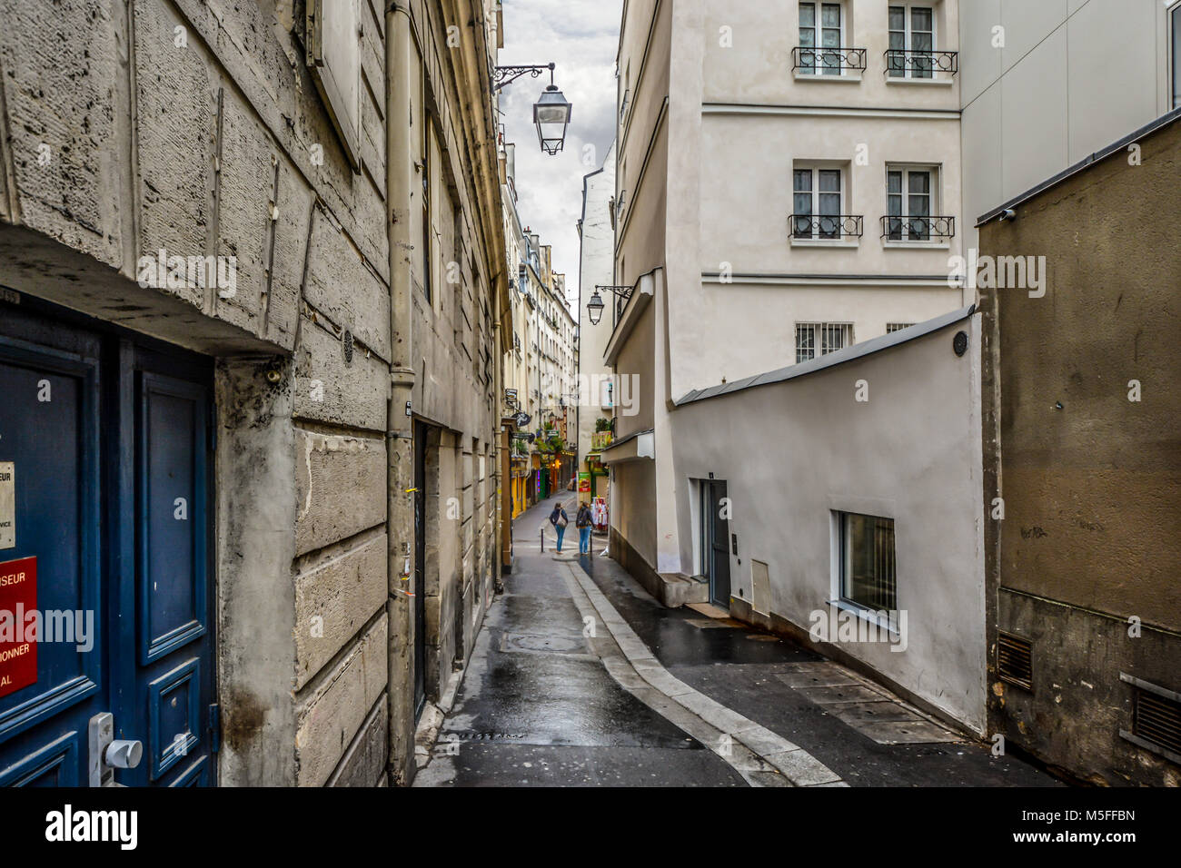 Dos señoritas en una caminata por la mañana en el Barrio Latino de París Francia pasan por un estrecho callejón en un día nublado. Foto de stock