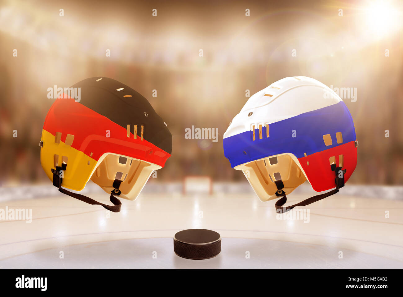 Ángulo de visión baja de hockey cascos pintados con Alemania y Rusia, banderas, y disco de hockey sobre hielo en el estadio iluminado de fondo. Foto de stock