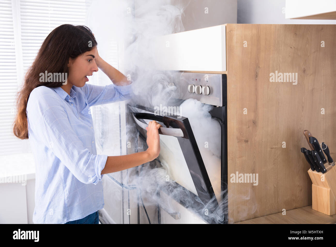 sello lamentar Tratamiento Preferencial Conmocionada Joven mirando el humo proveniente de microondas en la cocina  Fotografía de stock - Alamy