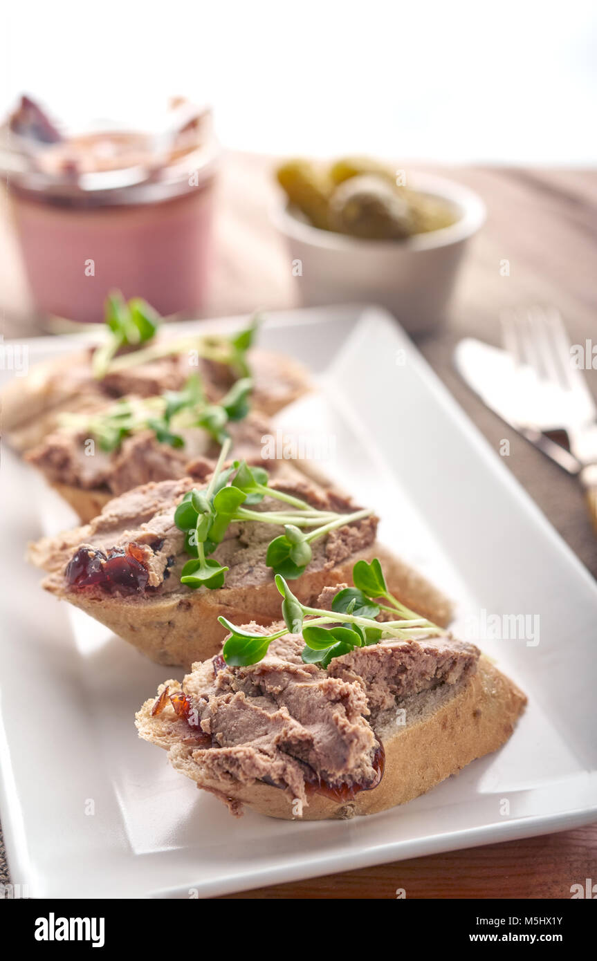 Hígado de pollo Pate esparcido en rebanadas de pan con verduras y condimentos. Foto de stock