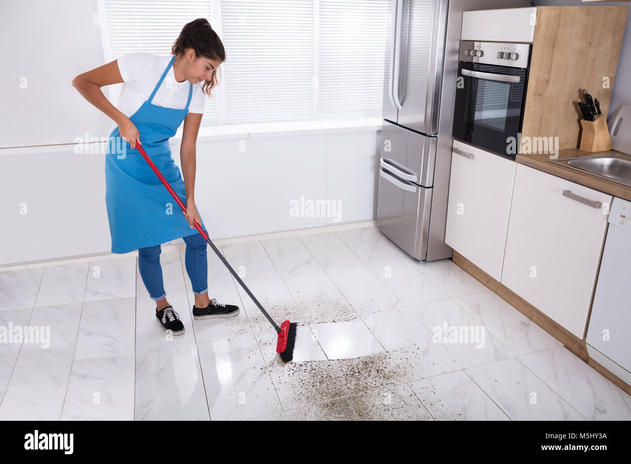 Fotos de Una Señora Limpieza Está Aspirando Suelo Cocina Con Una Escoba -  Imagen de © grigvovan #349364068