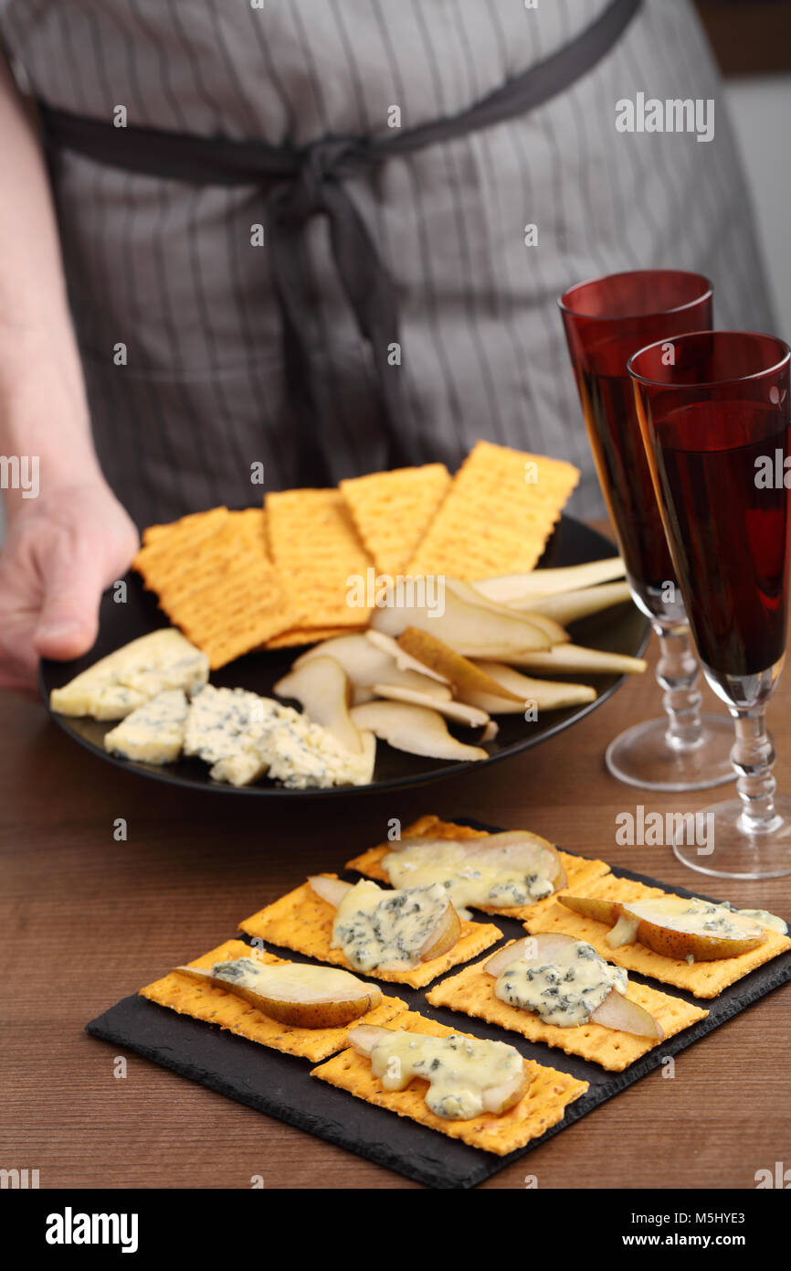 Hombre en el delantal sujetando la placa con ingredientes para el queso azul y pera sándwich Foto de stock