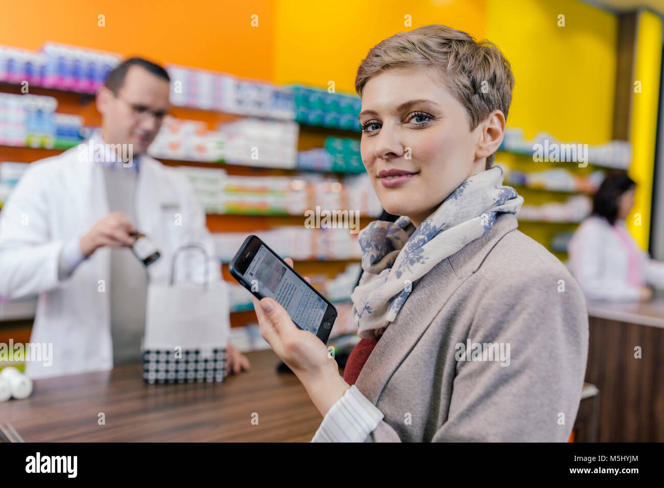 Retrato de mujer con teléfono celular en el mostrador de la farmacia  Fotografía de stock - Alamy