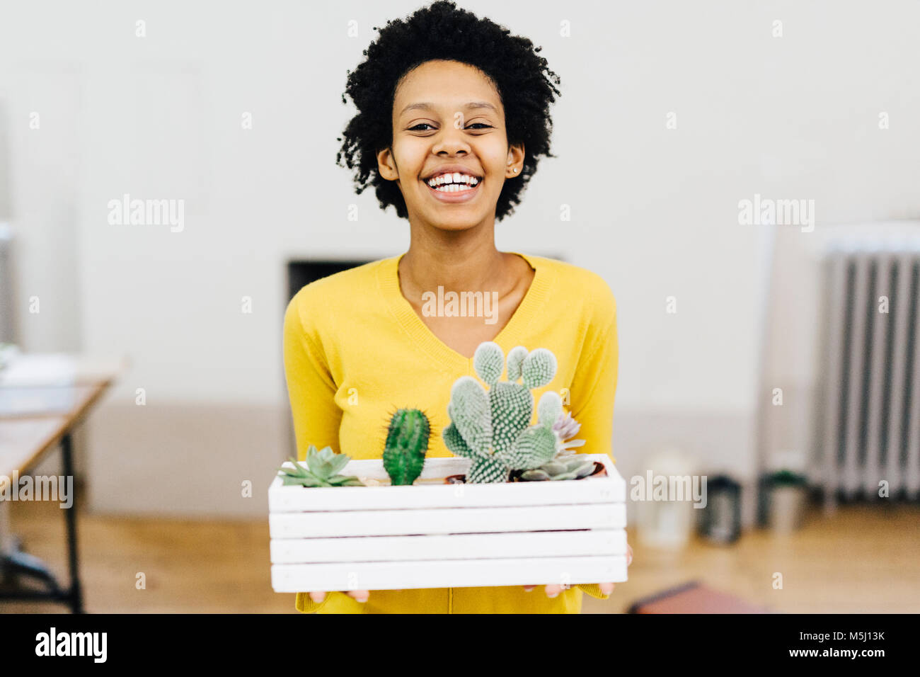 Mujer joven feliz celebración flor caja con cactus Foto de stock