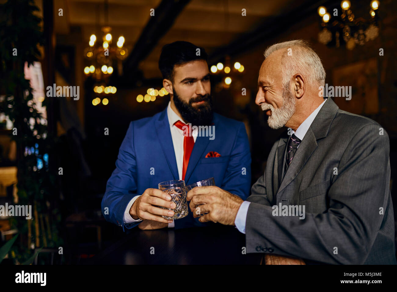 Dos hombres en un elegante bar vasos tintineo Foto de stock