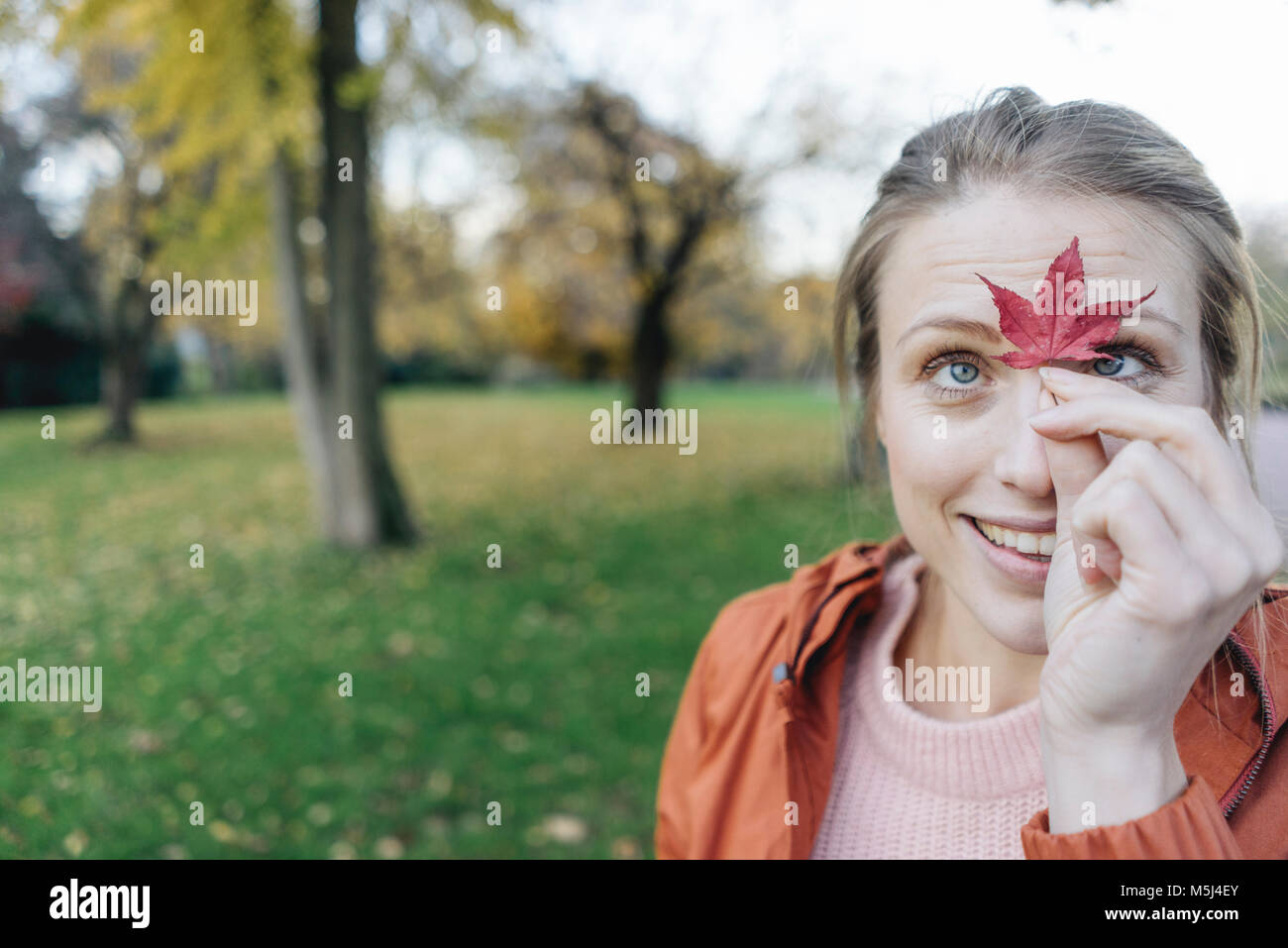 Retrato de mujer joven con hoja de otoño en un parque Foto de stock