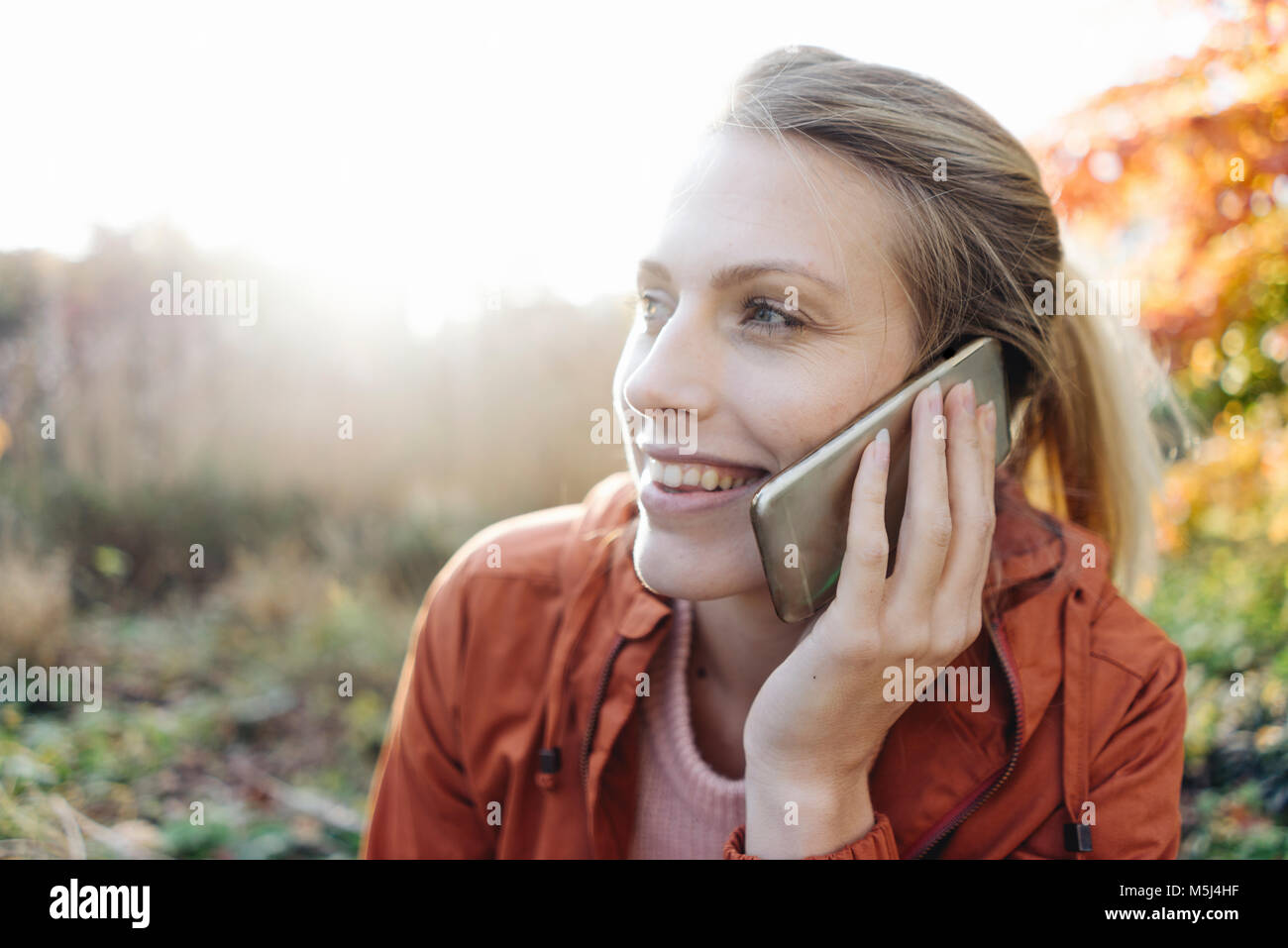 Retrato de mujer joven en el teléfono en el parque otoñal Foto de stock