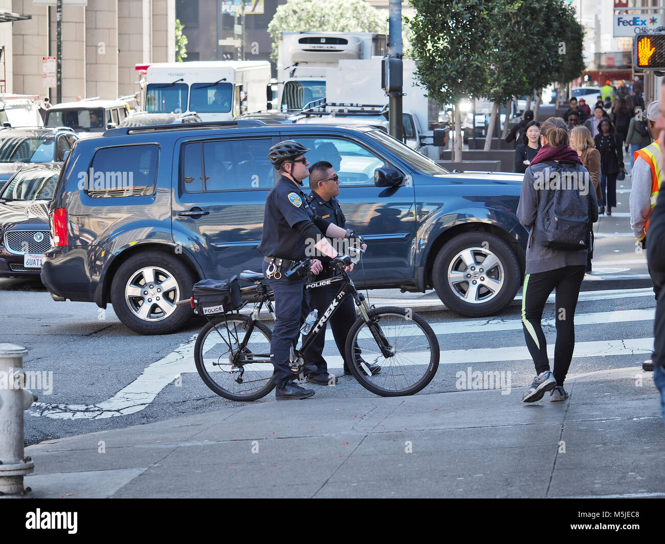 Dos oficiales del departamento de policía de San Francisco (uno en una bicicleta) sobre una calle, febrero de 2018 Foto de stock
