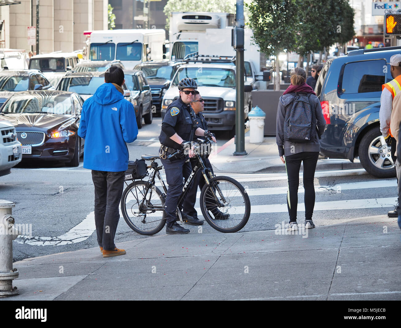 Dos oficiales del departamento de policía de San Francisco (uno en una bicicleta) sobre una calle, febrero de 2018 Foto de stock