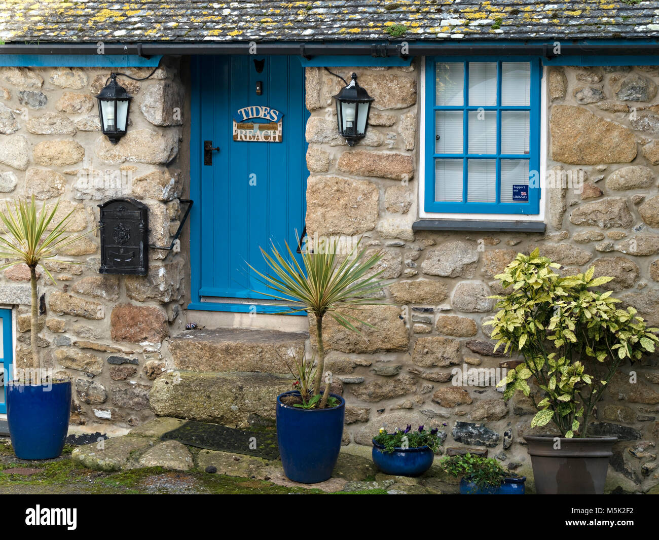 Bastante vieja piedra de granito de Cornualles Fisherman's Cottage llamado 'Tides alcanza' con puerta frontal azul, Mousehole, Cornwall, Inglaterra, Reino Unido. Foto de stock