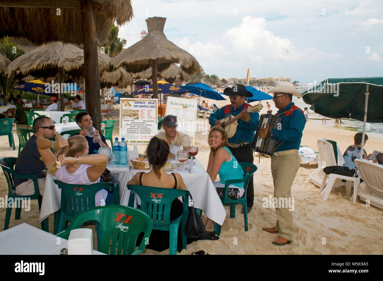 Músicos tocando una serenata mexicana en una mesa de un restaurante en la playa, la playa de Playa del Carmen, México, el Caribe Foto de stock