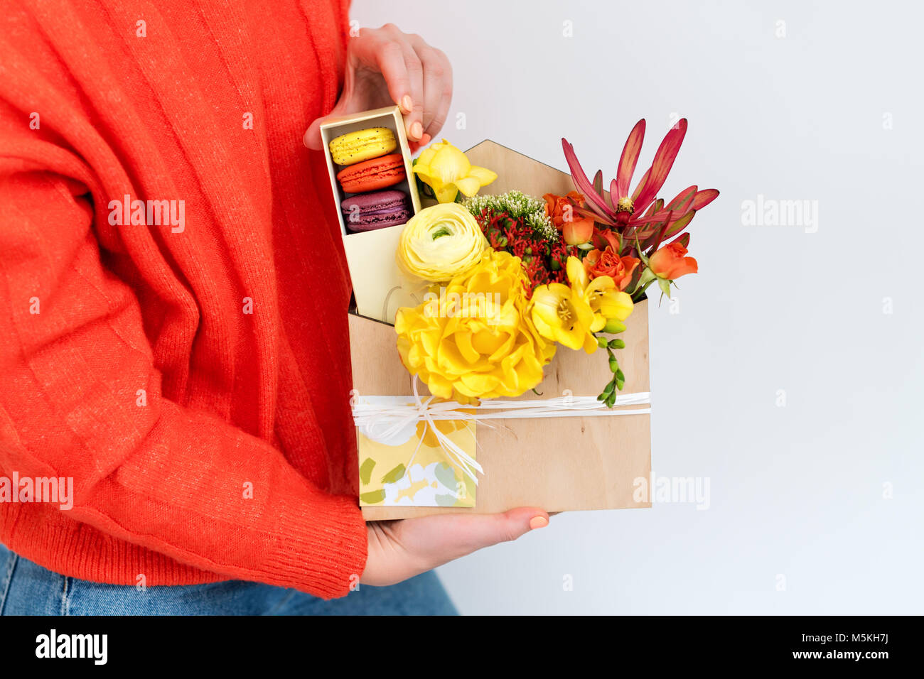 Mujer sosteniendo giftbox con flores y dulces. Macarrones y Ramo primaveral  en caja de madera Fotografía de stock - Alamy