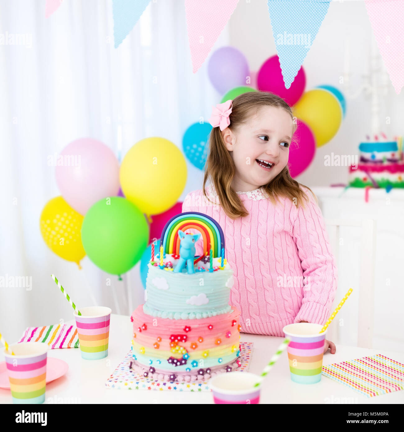 Fiesta de cumpleaños para niños con coloridas y decoración en tonos pastel  y unicornio arcoiris pastel. Niña con dulces, dulces y frutas. Globos y  banner en festivo Fotografía de stock - Alamy