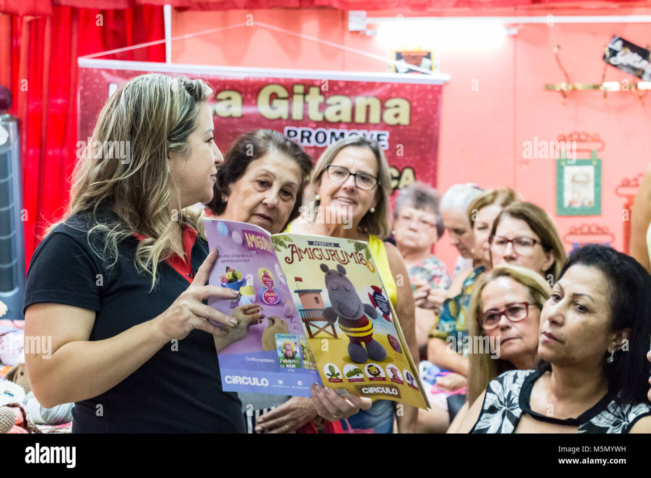 Itajaí, en Santa Catarina, Brasil - febrero 22th, 2018: Una maestra está mostrando una revista con tejido crochet patrones a sus alumnos en un knittin Foto de stock