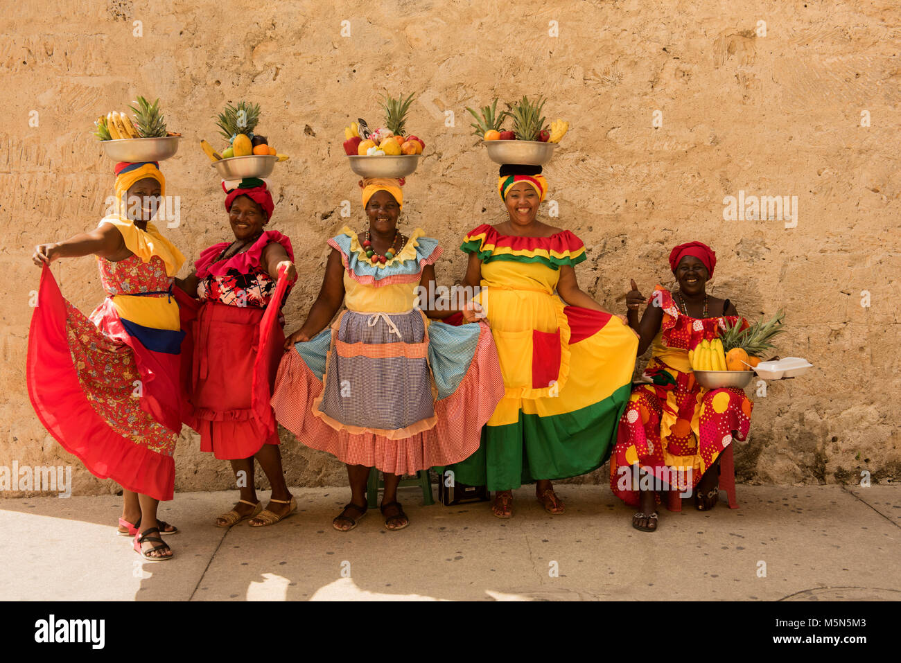 La mujer en coloridos trajes locales plantean con cestas de fruta en Cartagena, Colombia. Foto de stock