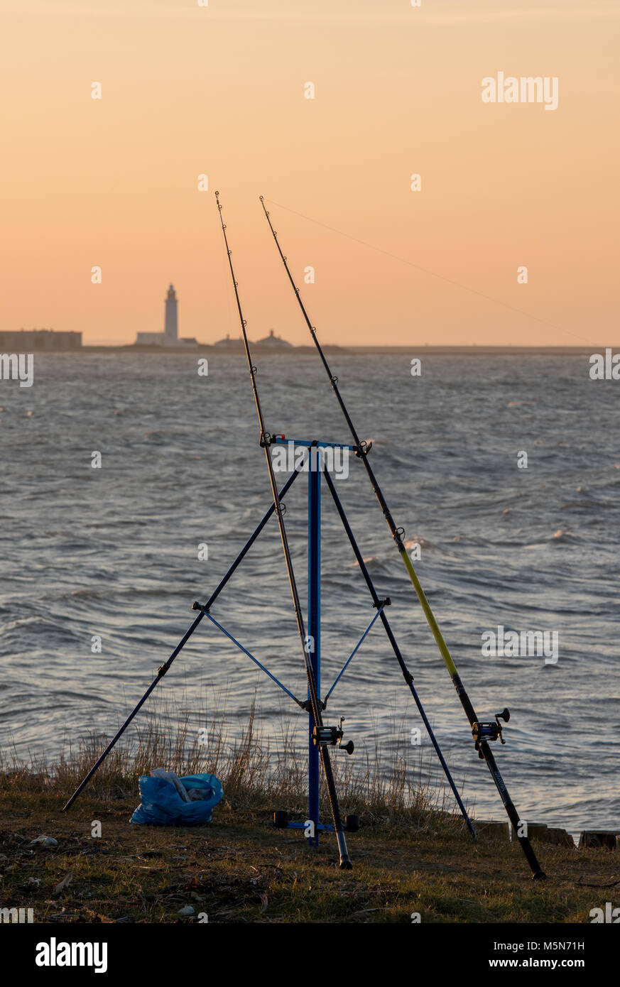 Dos cañas de pescar en la playa en la costa de la isla de Wight, mirando  hacia el castillo de Hurst en keyhaven cerca de Milford en mar, Hampshire.  Pesca deportiva y