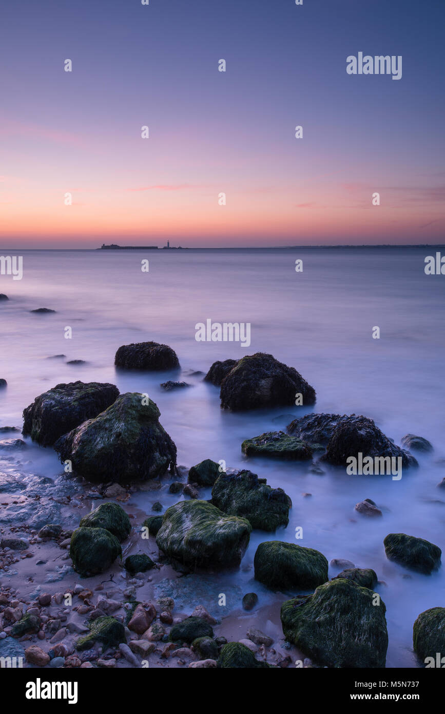 Un hermoso y tranquilo paisaje atmosférico o paisaje de la costa de la Isla de Wight en Sunset con rocas en la zona del embalse y tranquilo mar místico. Foto de stock