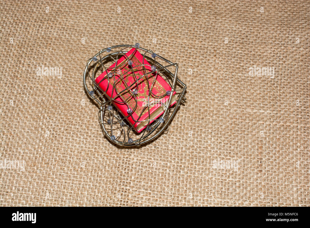 El Sagrado Corán en tamaño mini en una jaula en forma de corazón Foto de stock