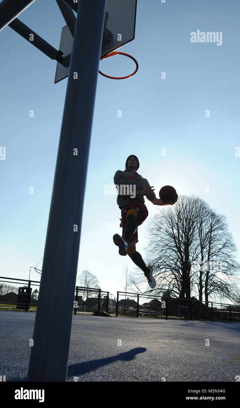 Un rodaje en exteriores de un jugador de baloncesto en Devizes, Wiltshire. Rodada en la luz solar natural en una cancha de baloncesto. Amplia profundidad de archivado, con buena iluminación. Foto de stock