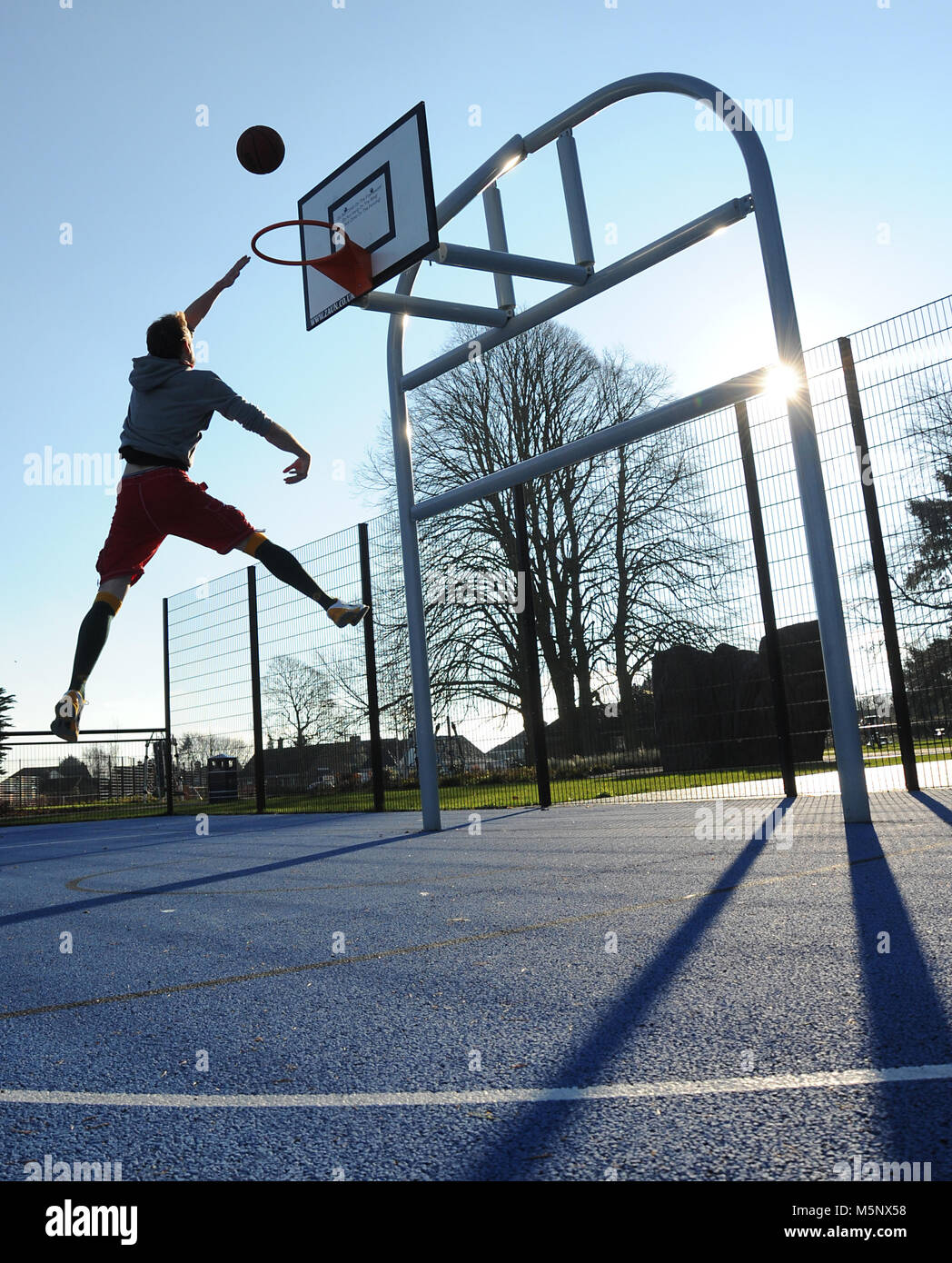 Un rodaje en exteriores de un jugador de baloncesto en Devizes, Wiltshire. Rodada en la luz solar natural en una cancha de baloncesto. Amplia profundidad de archivado, con buena iluminación. Foto de stock