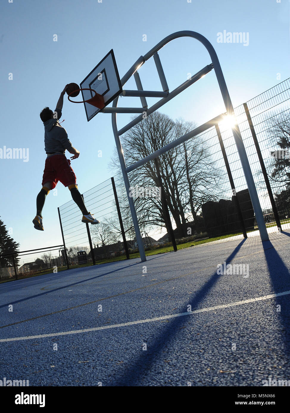 Un rodaje en exteriores de un jugador de baloncesto en Devizes, Wiltshire. Rodada en la luz solar natural en una cancha de baloncesto. Amplia profundidad de archivado, con buena iluminación. Foto de stock