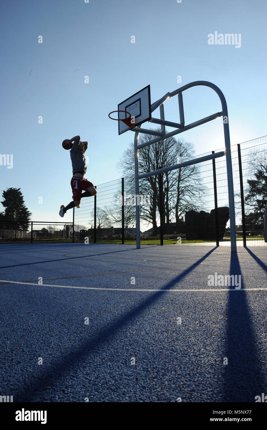 Un rodaje en exteriores de un jugador de baloncesto en Devizes, Wiltshire. Rodada en la luz solar natural en una cancha de baloncesto. Amplia profundidad de archivado, con buena iluminación. Foto de stock