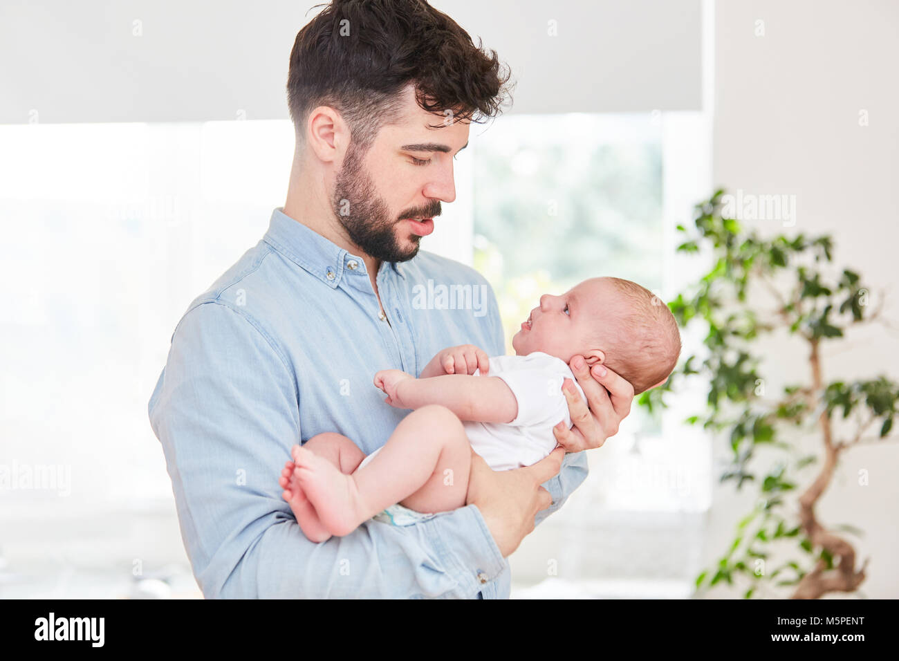 El hombre como un padre amoroso feliz mira a su bebé recién nacido  Fotografía de stock - Alamy