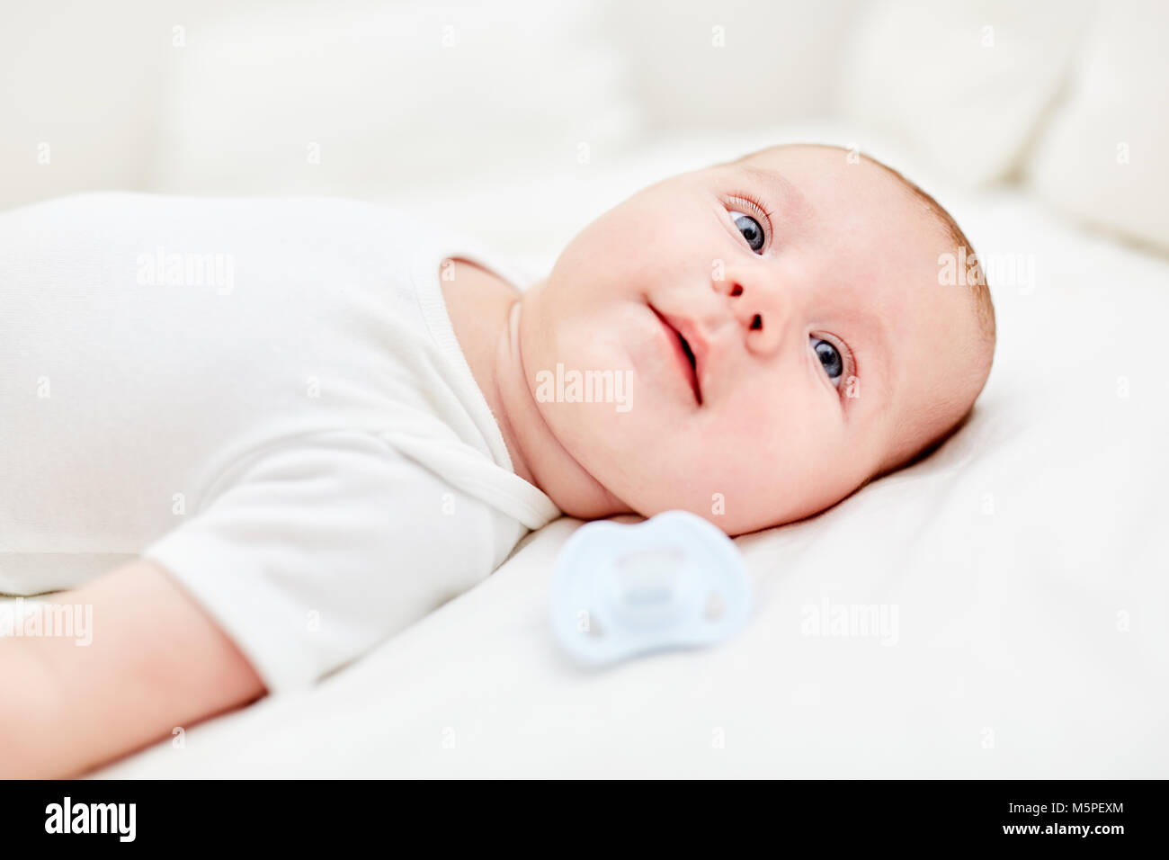 Bebé recién nacido yace sobre su espalda y parece curioso y alerta Foto de stock