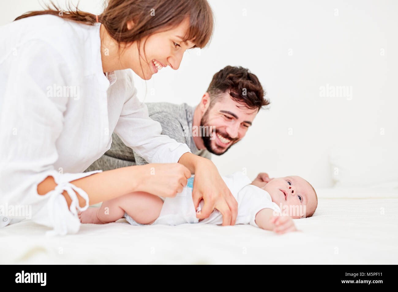 Los padres, los cuidadores hacer un cambio de pañal con su pequeño bebé Foto de stock