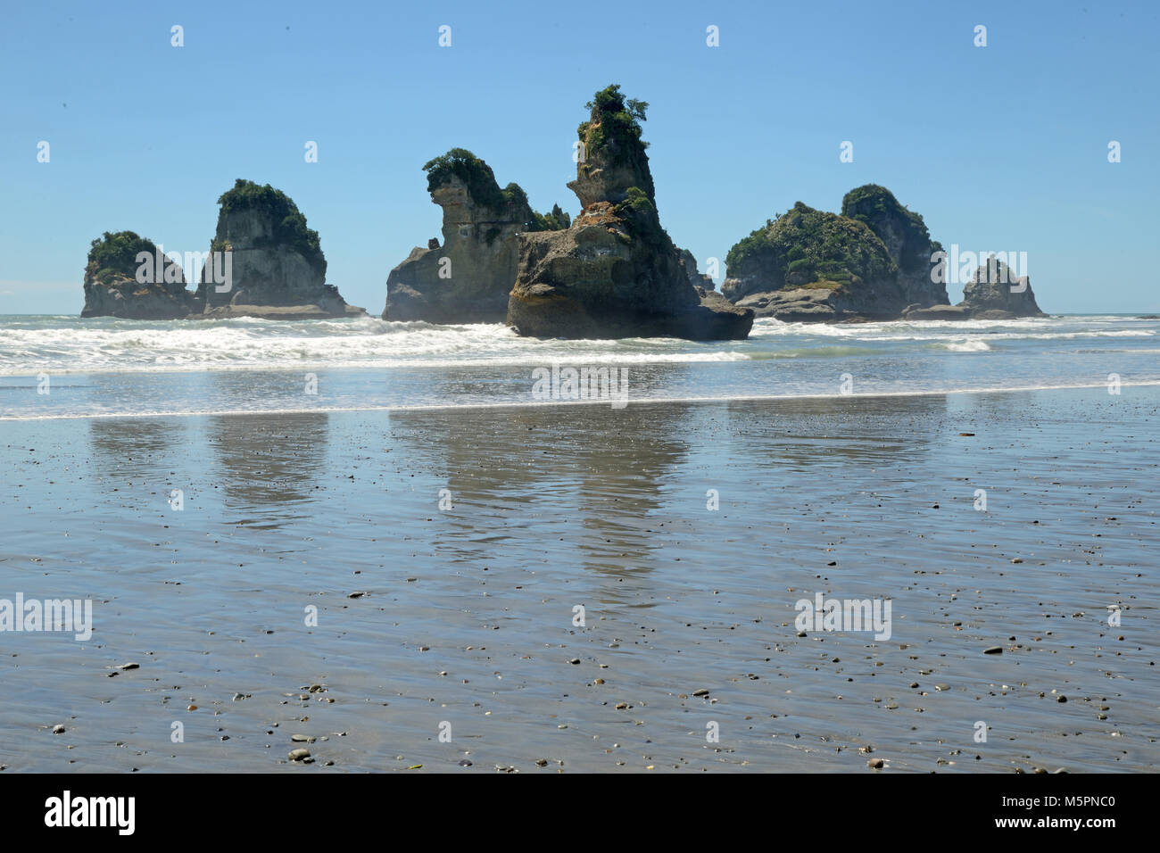 Marea baja en una playa de la costa oeste revela un grupo de pequeñas islas, Isla del Sur, Nueva Zelanda Foto de stock