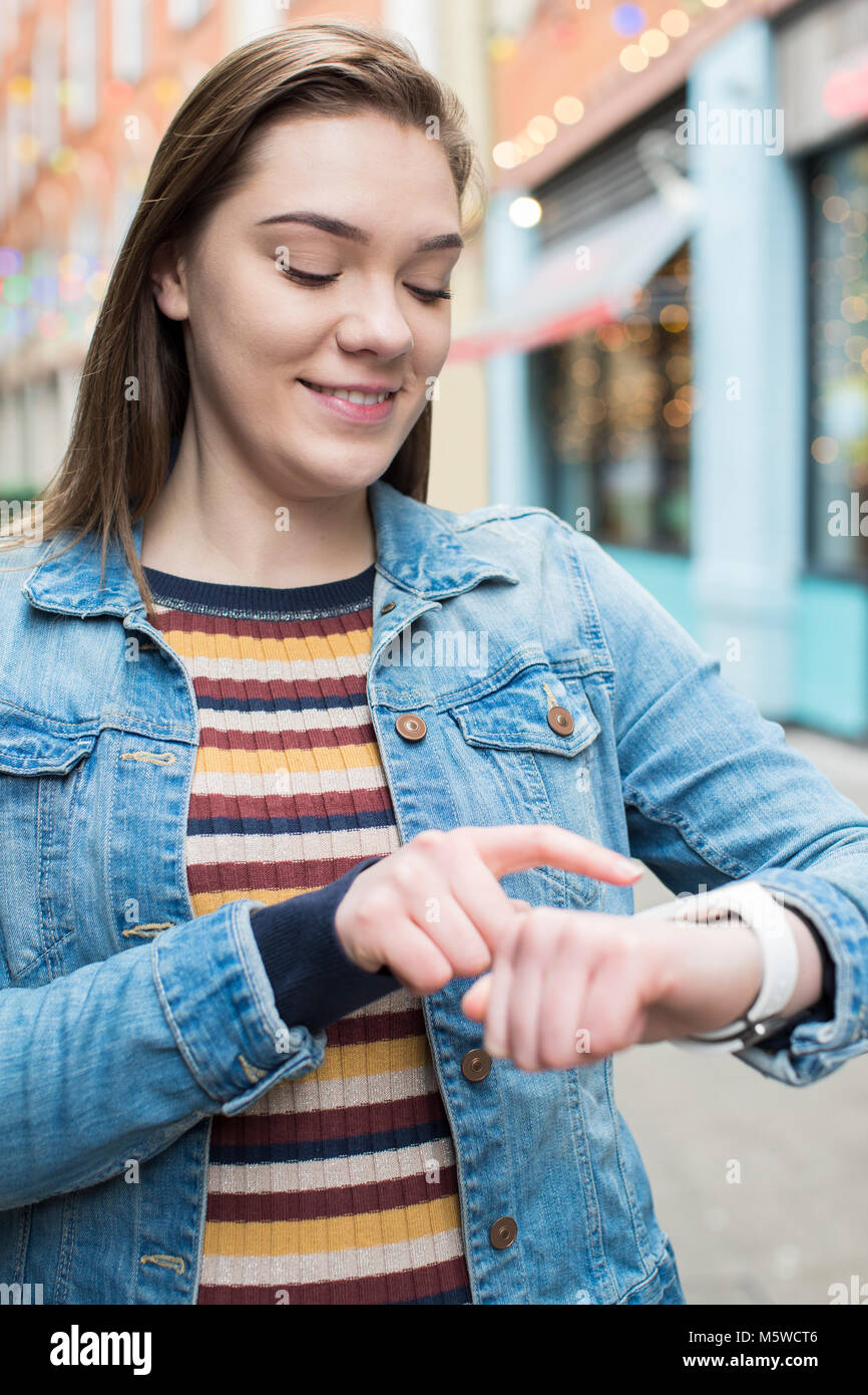 Mujer caminando por las calles de la ciudad usando Smart Watch Foto de stock