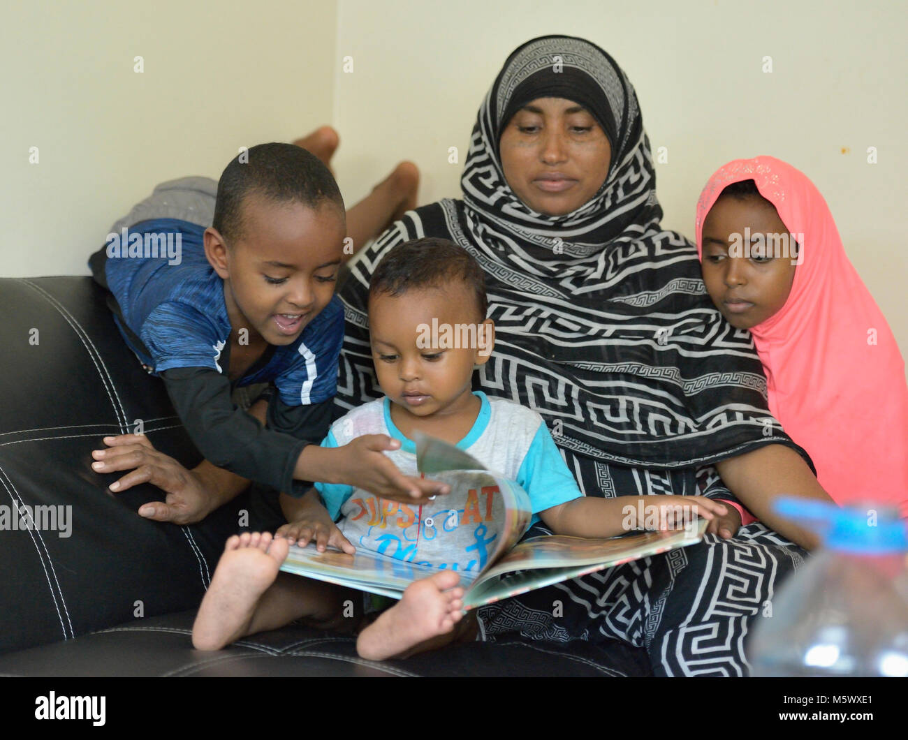 Kebir Mekiya y sus hijos, los refugiados recién llegados procedentes de Eritrea, explorar un libro en su apartamento en Lancaster, Pennsylvania. Foto de stock