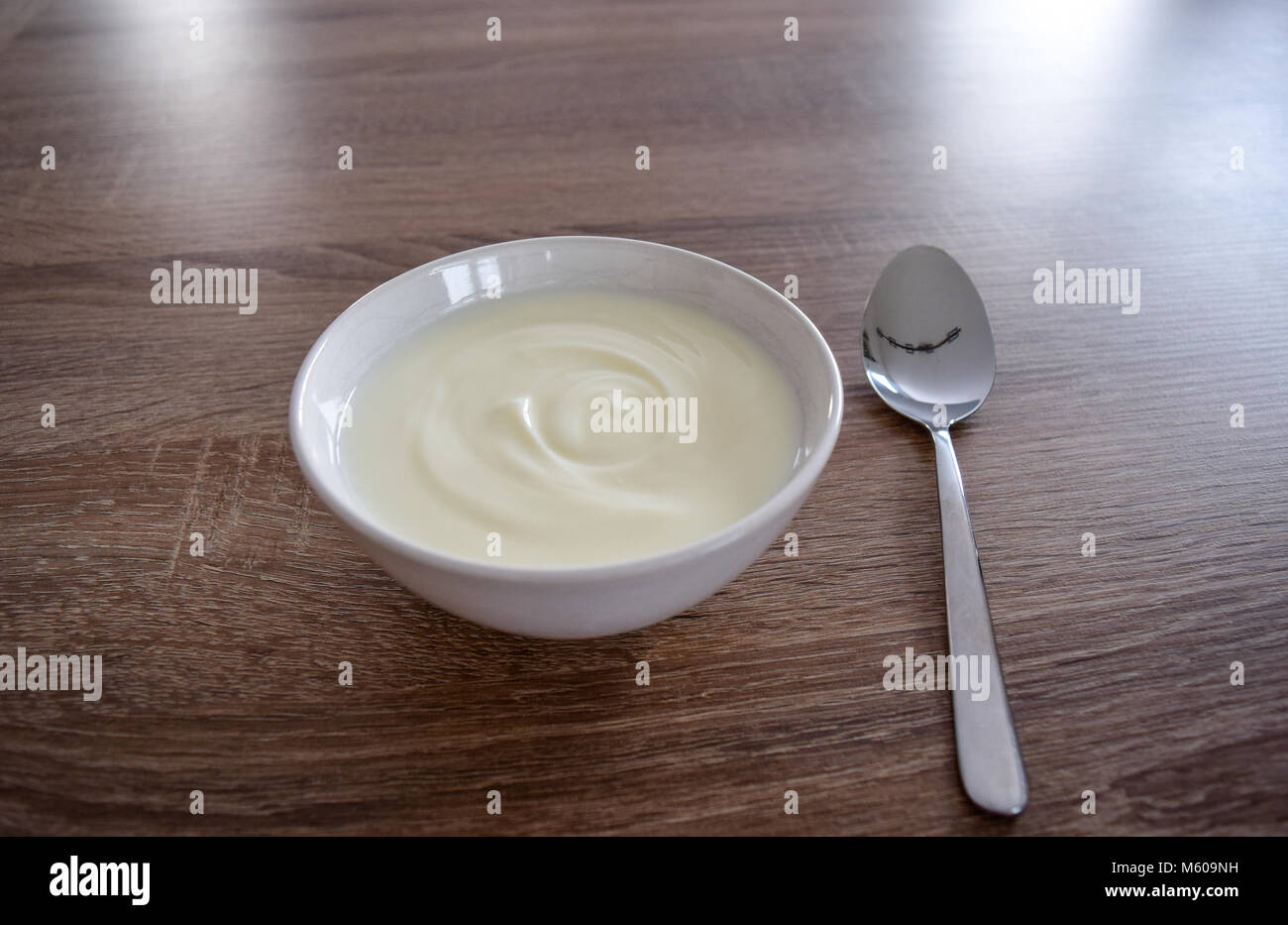 Cuenco de cerámica blanca de yogur aislado sobre fondo de madera y una